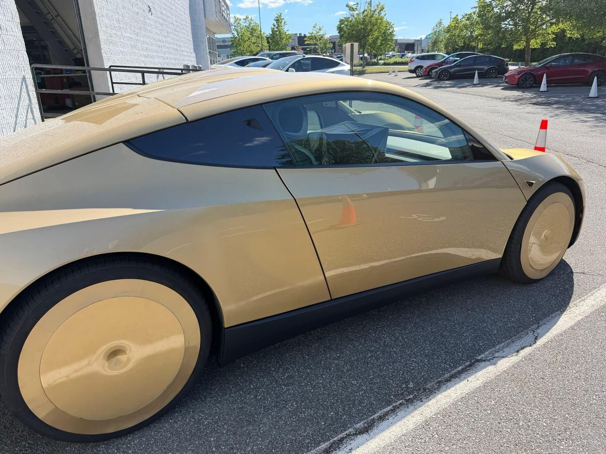 Side profile of a gold-camo Tesla Cybercab test unit at Tesla Peabody